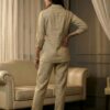 Back view of a minimalist beige cotton-linen matching two-piece ensemble for women, highlighting the clean, tailored drape of the 3/4th sleeve shirt and straight-leg pants.