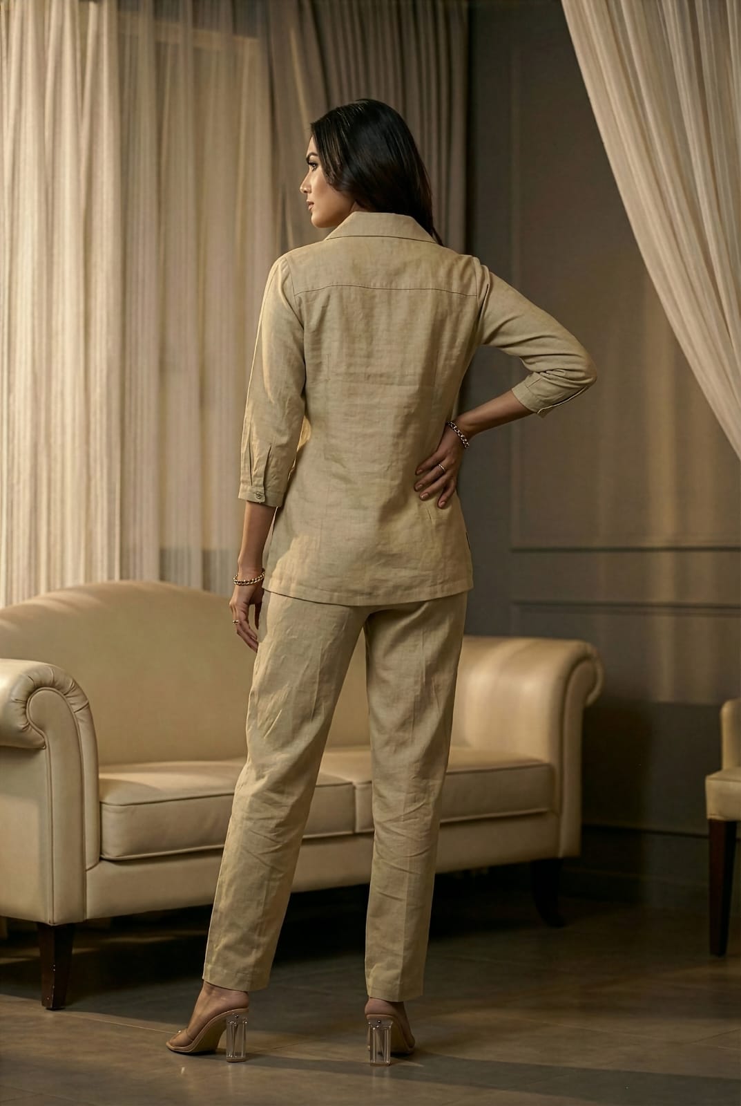 Back view of a minimalist beige cotton-linen matching two-piece ensemble for women, highlighting the clean, tailored drape of the 3/4th sleeve shirt and straight-leg pants.