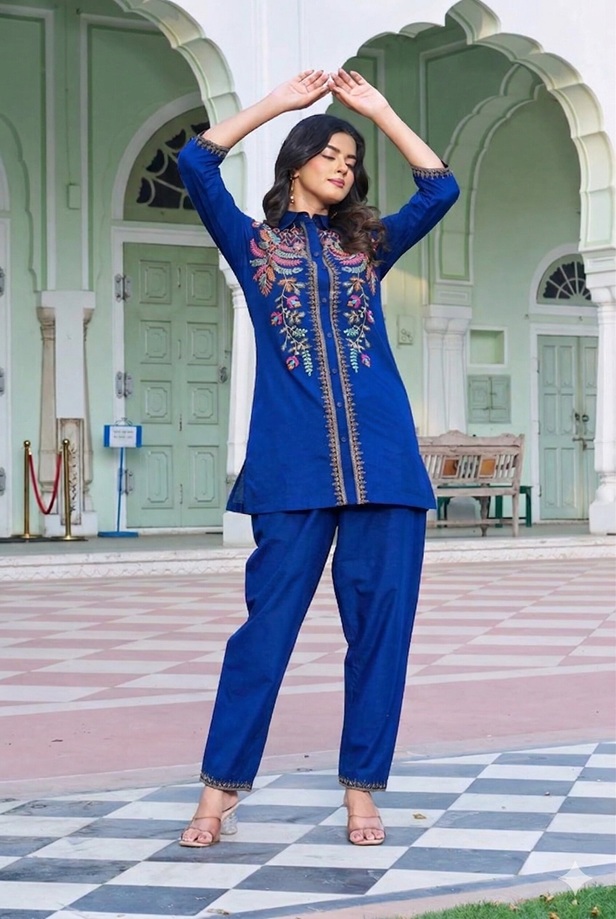 Royal-Blue-Floral-Embroidered-Flex-Cotton-Co-ord-Set-front Royal Blue Floral Embroidered Flex-Cotton Co-ord Set - A woman wearing a royal blue floral embroidered flex-cotton co-ord set with a sharp collar shirt and tapered trousers.