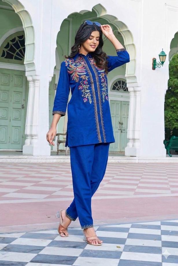 Royal-Blue-Floral-Embroidered-Flex-Cotton-Co-ord-Set-styled-left-profile Left side profile of a woman in a royal blue embroidered tunic shirt showing the floral detailing on the sleeve and side-slit hem.