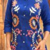 Close-up of multi-color floral embroidery and frayed collar on a cobalt blue linen shirt.