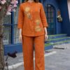 Rust Linen Embroidered 2-Piece Co-ord Set - A full-length shot of a girl modeling a vibrant, burnt-orange linen tunic with matching trousers featuring floral details.