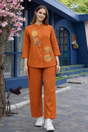 Rust Linen Embroidered 2-Piece Co-ord Set - A full-length shot of a girl modeling a vibrant, burnt-orange linen tunic with matching trousers featuring floral details.