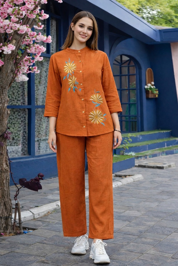 Rust Linen Embroidered 2-Piece Co-ord Set - A full-length shot of a girl modeling a vibrant, burnt-orange linen tunic with matching trousers featuring floral details.