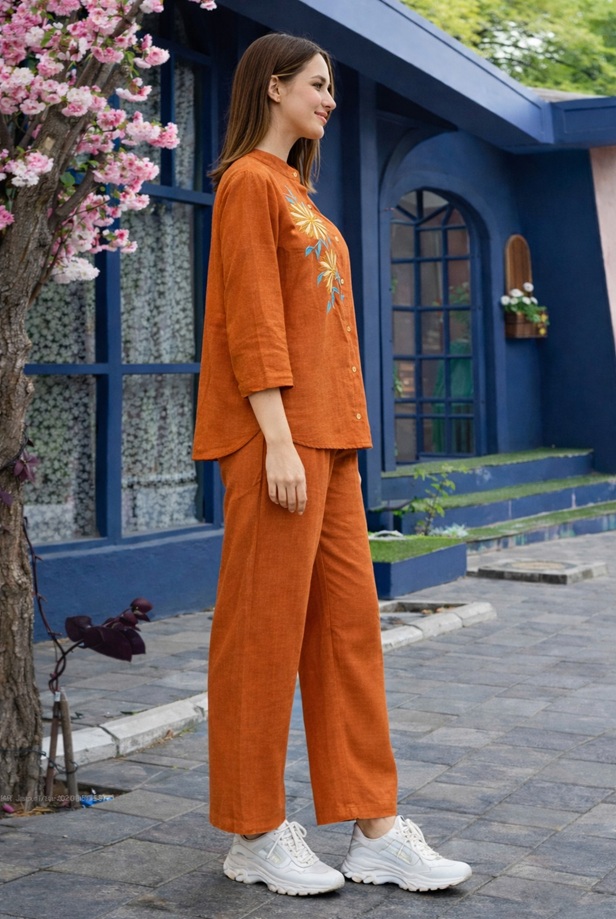 Side profile of the rust linen embroidered 2-piece co-ord set, showing the drape and relaxed fit of the top and trousers.