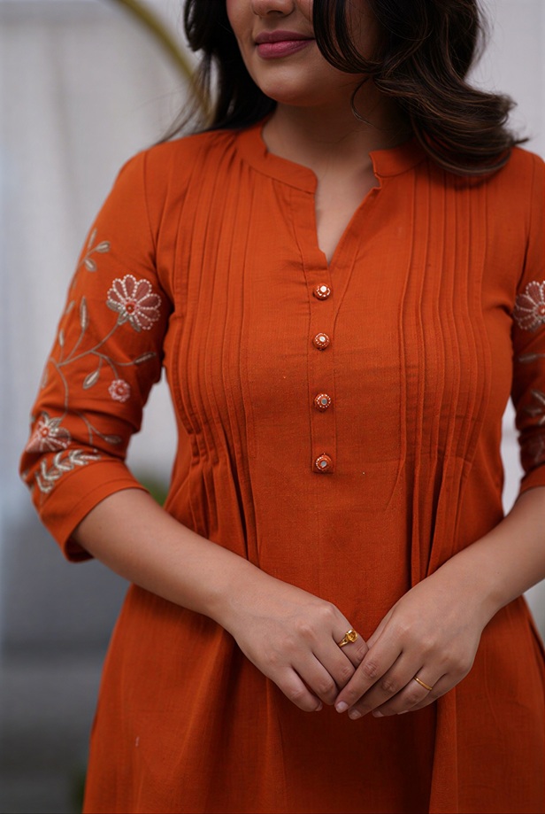 Close-up of the delicate pin-tuck detailing and mandarin collar on the warm rust tunic co-ord set.