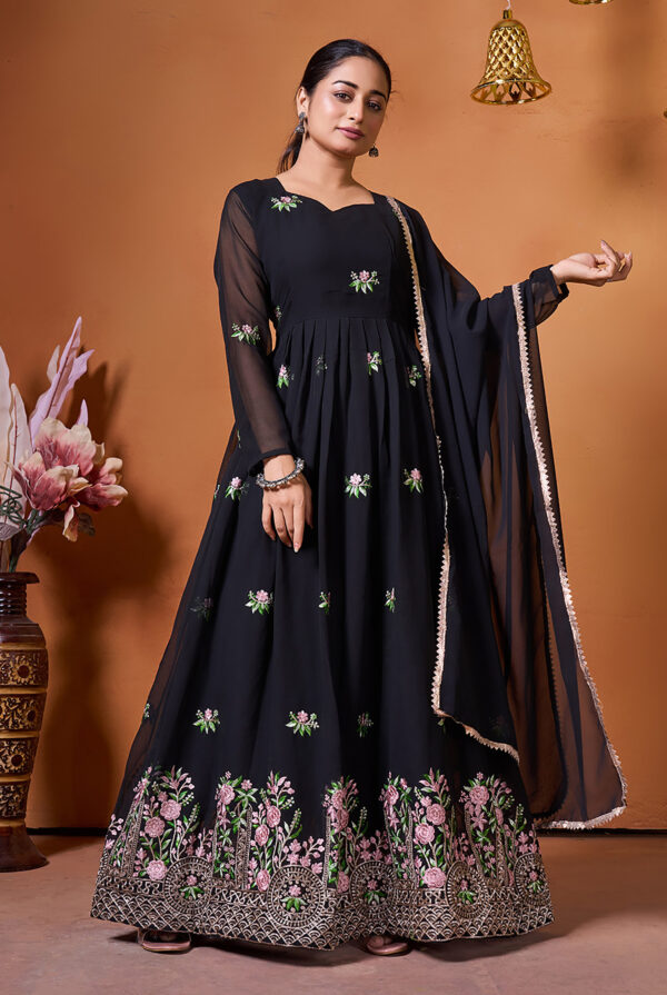 A woman wearing a floor-length black Anarkali gown with pink floral embroidery and a sheer dupatta.