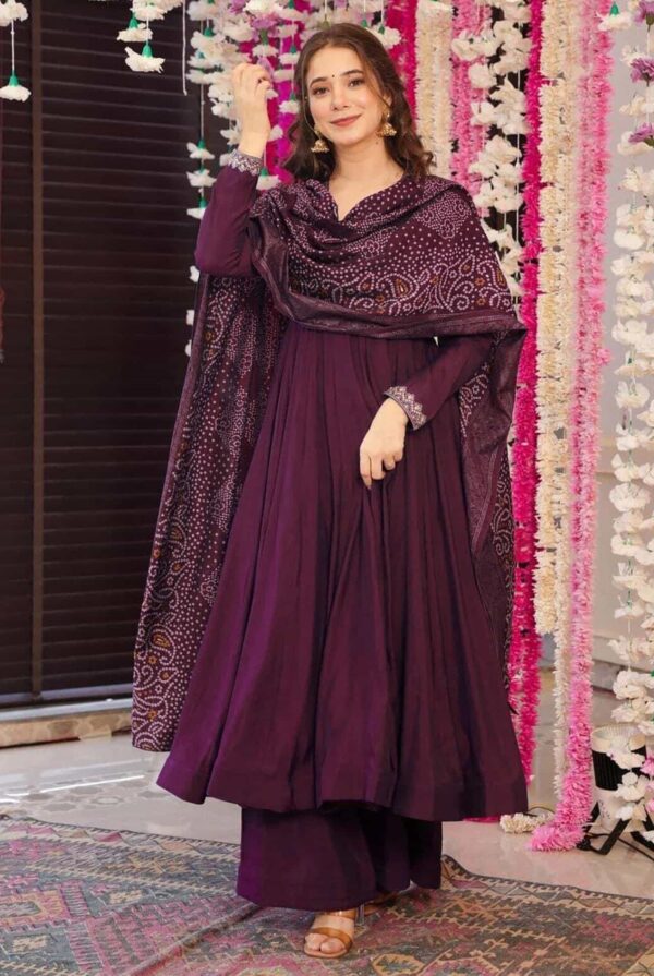 A woman wearing a deep wine-colored flared Anarkali kurta with silver neckline embroidery and a matching Bandhani print dupatta.