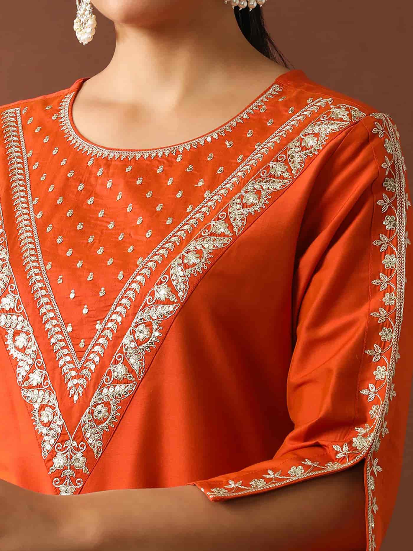 Macro shot of silver zari embroidery on a sapphire blue silk neck and small floral buttis scattered across the fabric.