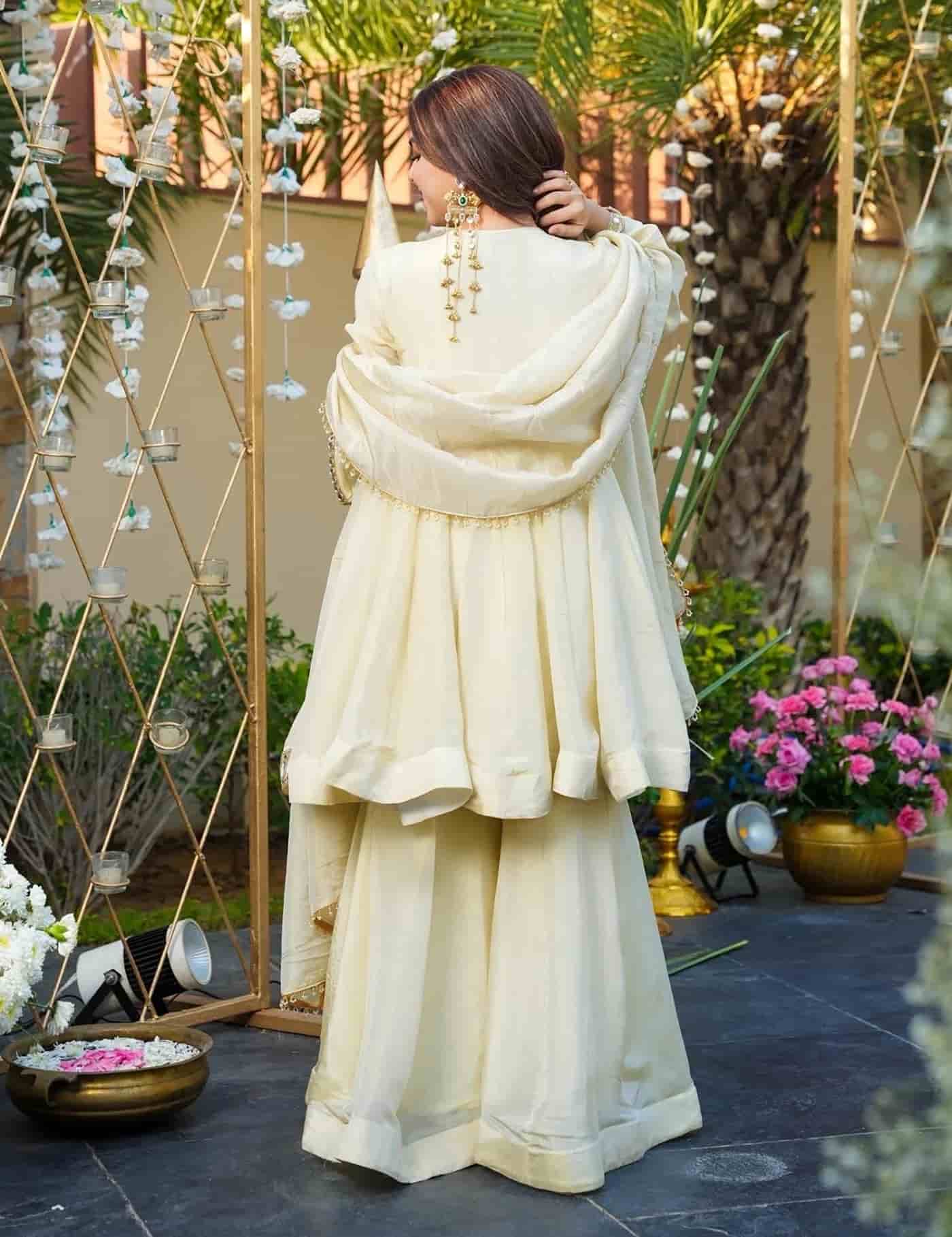 Rear view of an ivory organza peplum kurta showing a deep V-back design and a sweeping flared hem.