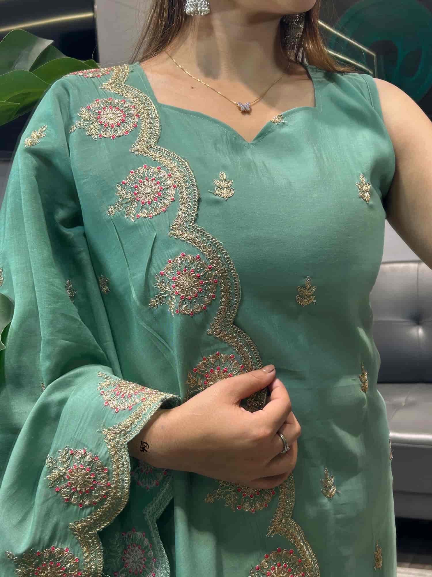 Macro detail of gold thread embroidery on the scalloped edges of a mint green organza dupatta.