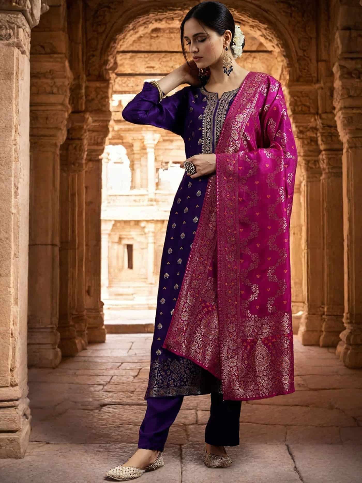 A woman wearing a premium amethyst purple silk kurta with gold zari neck detailing and a contrast magenta dupatta.