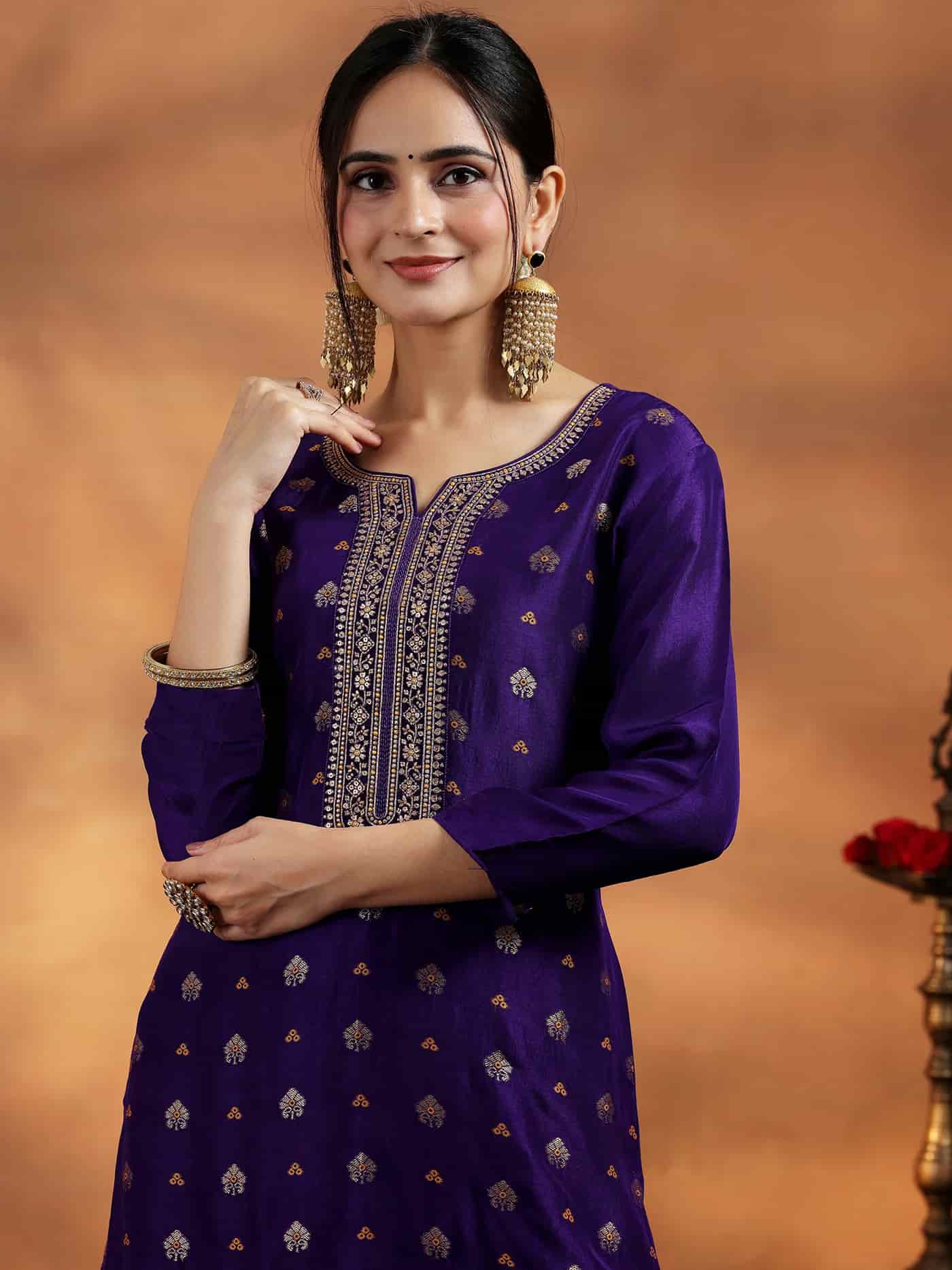 Macro detail of gold threadwork on a purple silk neck and the rich texture of a pink Banarasi weave.