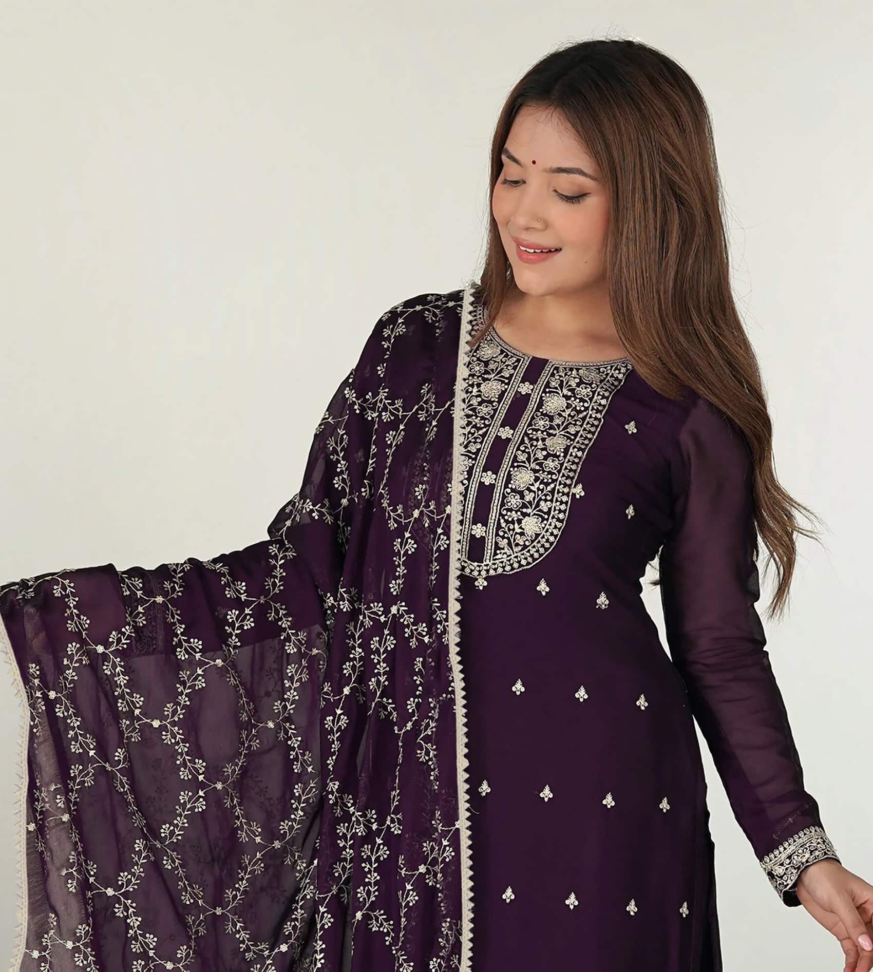 Detailed close-up of silver threadwork and floral patterns on dark purple fabric.