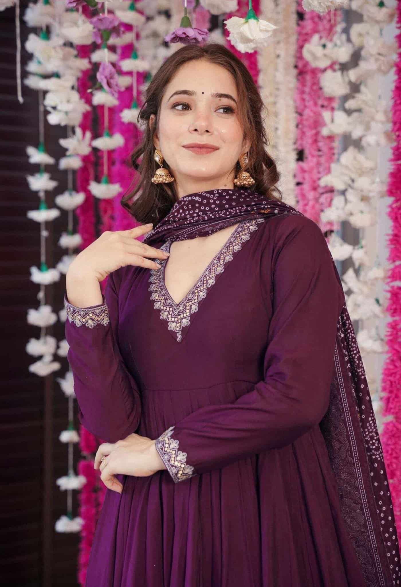 Macro shot of silver threadwork on a wine-colored neckline next to the traditional white and orange dot patterns of a Bandhani dupatta.