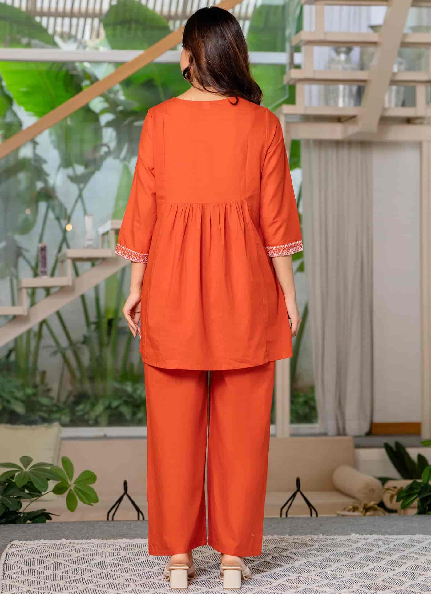 Rear view of a deep burnt orange silk Anarkali showing a clean back design and the sweeping, floor-length volume of the skirt.