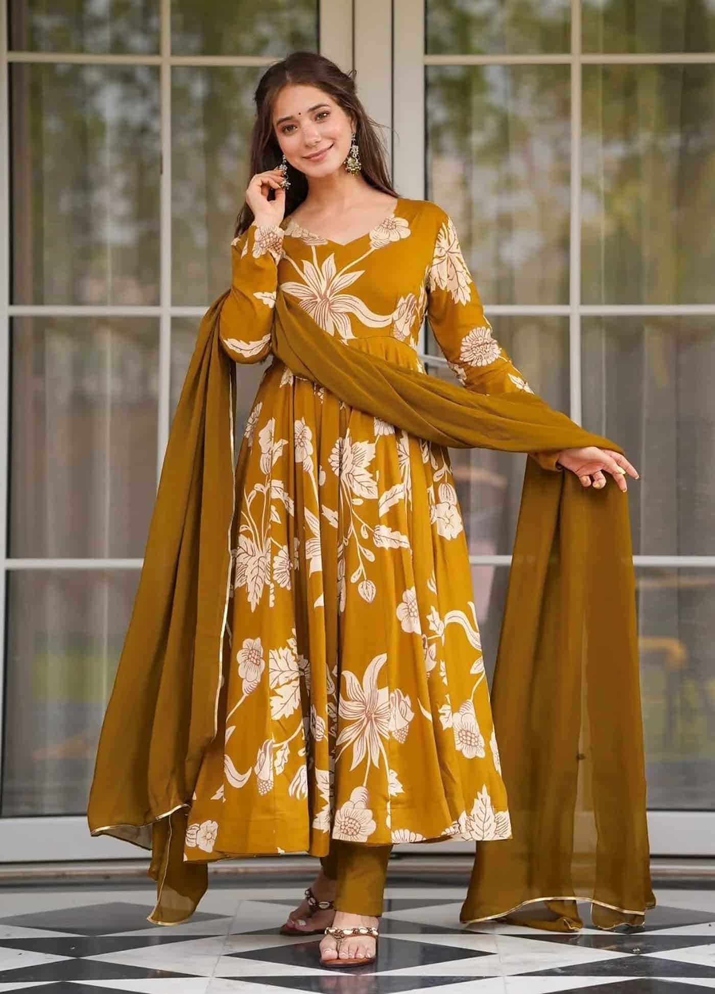 A woman wearing a mustard yellow floor-length Anarkali with large white floral prints and a matching dupatta.