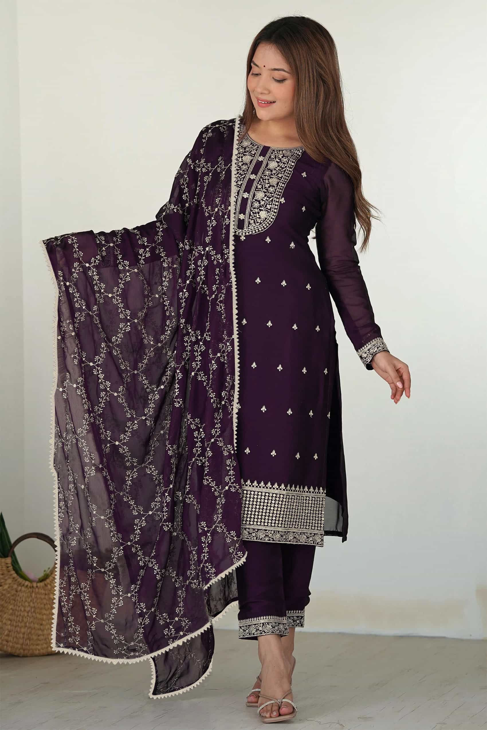 A woman wearing a deep plum purple straight-fit kurta with silver zari embroidery and a matching dupatta.