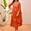 A woman in a burnt orange A-line silk kurta featuring ivory floral embroidery on the yoke and matching straight-fit pants.