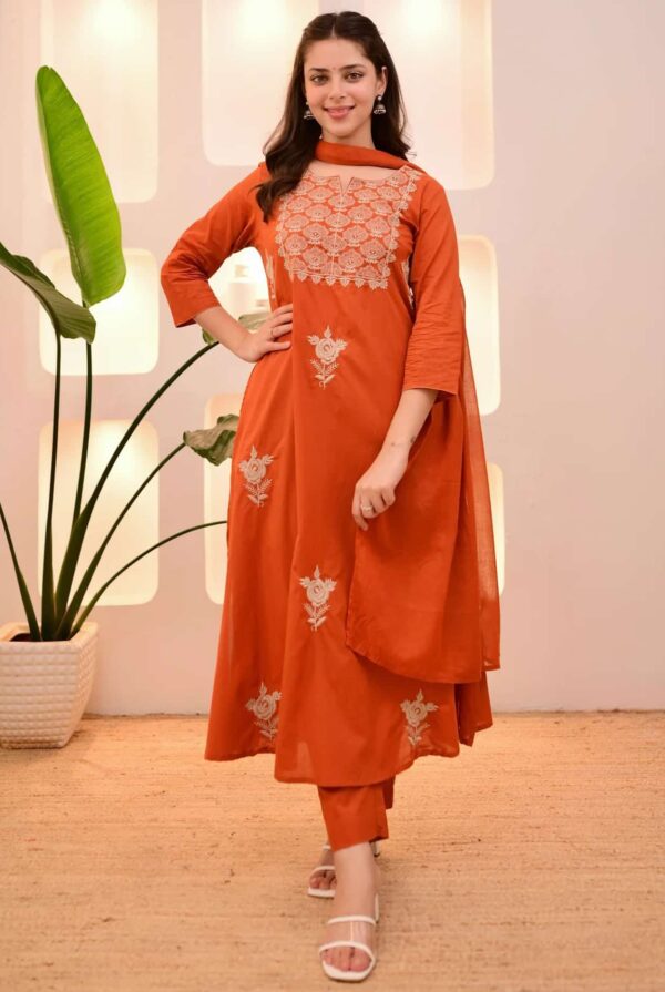 A woman in a burnt orange A-line silk kurta featuring ivory floral embroidery on the yoke and matching straight-fit pants.