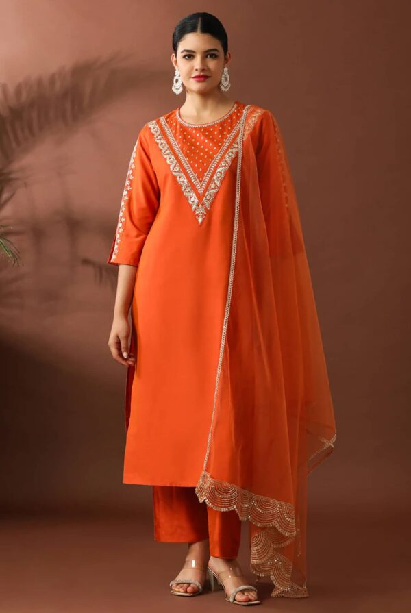 A woman in a deep sapphire blue straight-fit silk kurta featuring a silver embroidered V-neckline and matching pants.