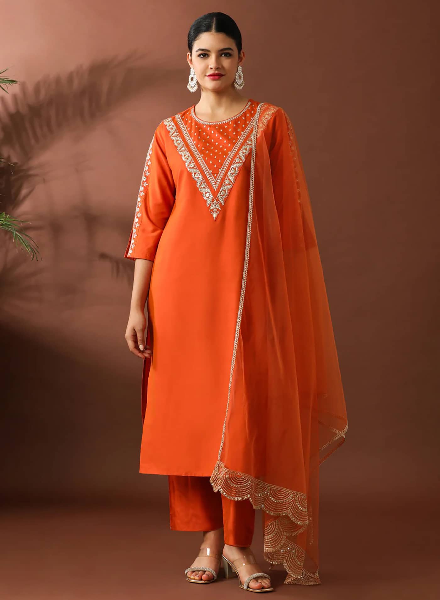 A woman in a deep sapphire blue straight-fit silk kurta featuring a silver embroidered V-neckline and matching pants.