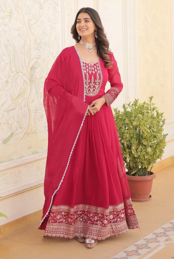 A woman in a premium scarlet red Anarkali gown with intricate silver zari embroidery on the bodice.