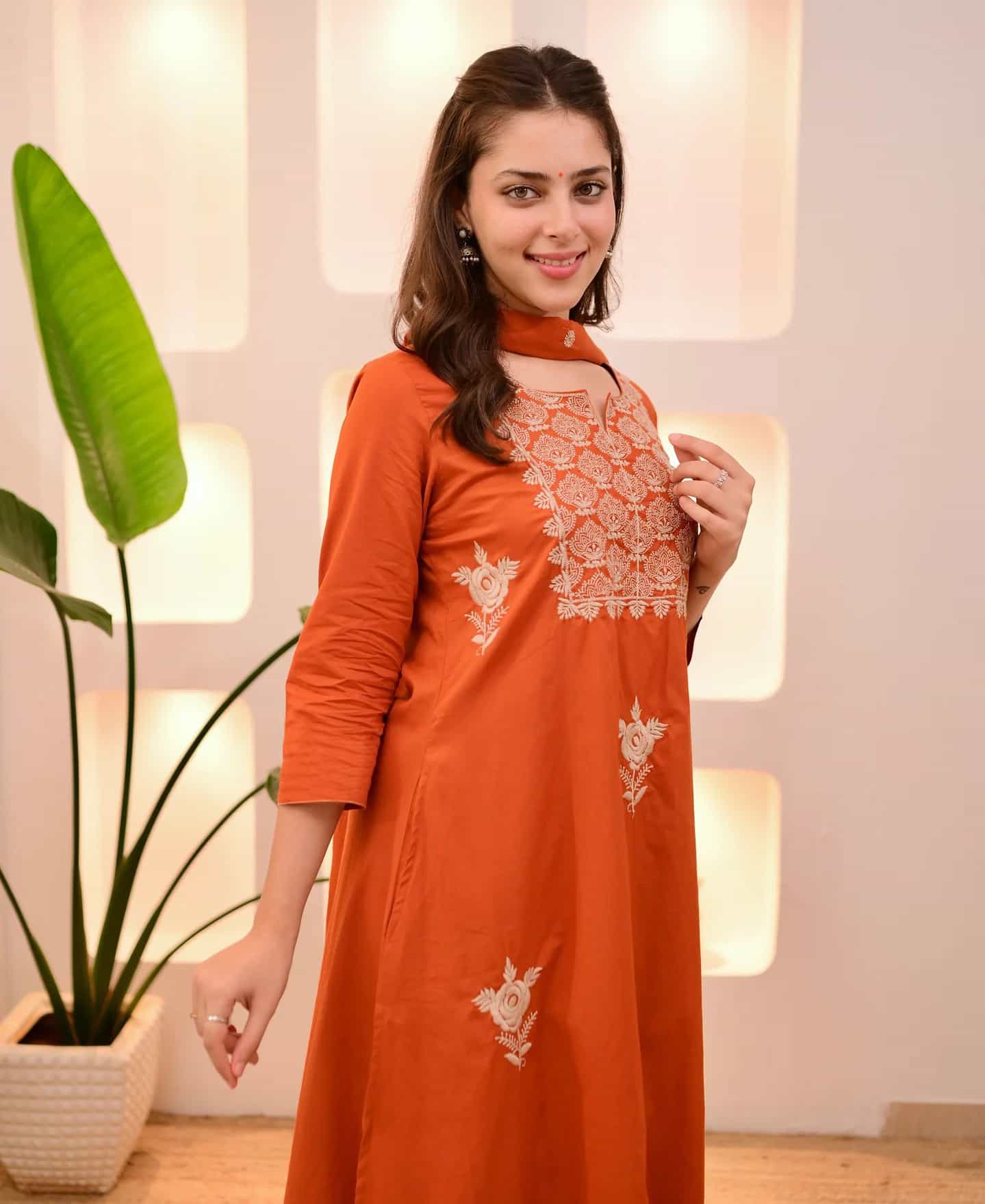 Side profile of an orange embroidered silk kurta highlighting the three-quarter sleeves and fluid drape.