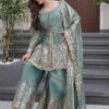 Side profile of a seafoam green suit highlighting the tiered sharara flare and the delicate gold-bordered dupatta.