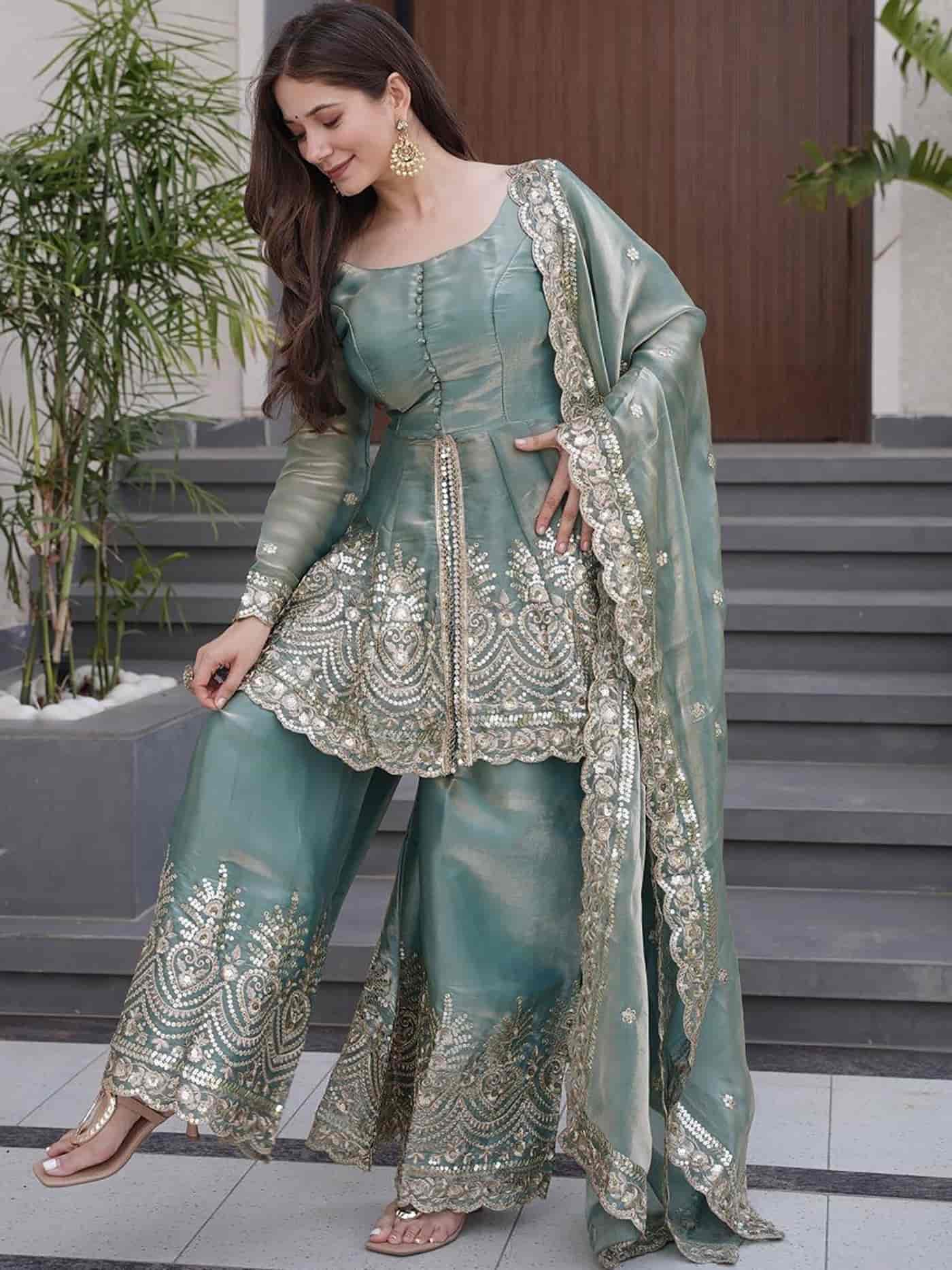 Side profile of a seafoam green suit highlighting the tiered sharara flare and the delicate gold-bordered dupatta.