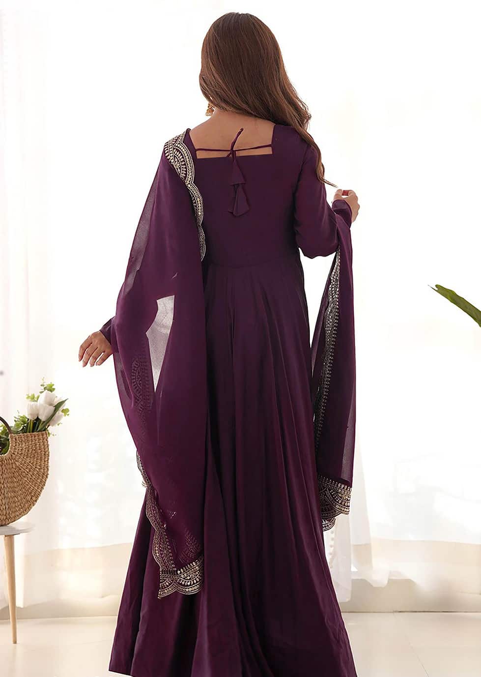 Back view of a wine-colored ethnic gown showing a square neckline with tie-up tassel details and a scalloped border dupatta.